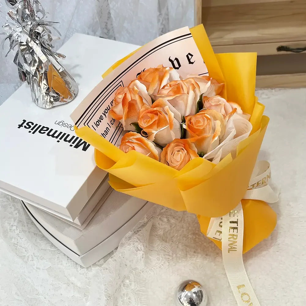 A bouquet of orange and cream artificial roses presented in a yellow paper wrapping.