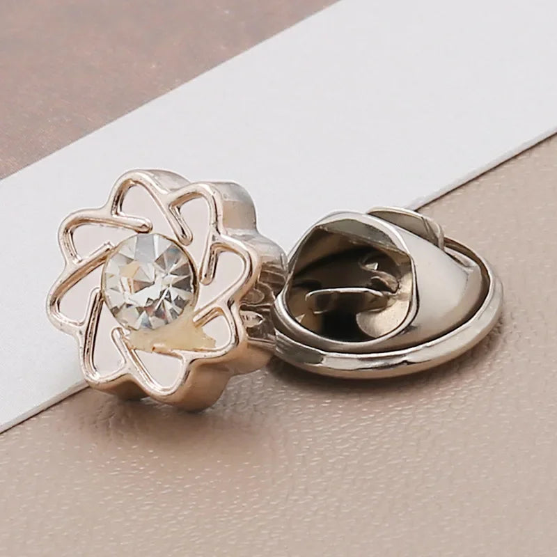 A pair of gold-toned pearl and rhinestone no-sew brooch buttons for crafting.