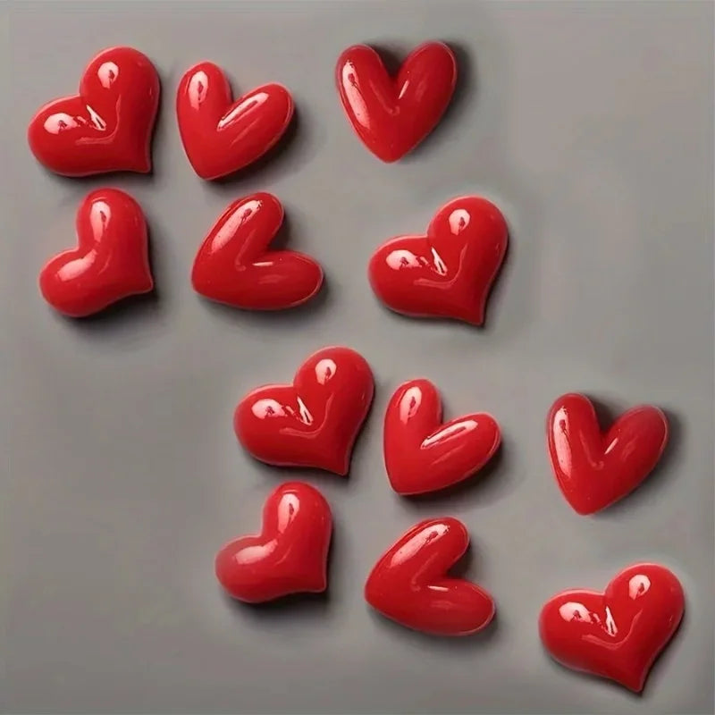 A collection of glossy red heart-shaped fridge magnets arranged on a gray surface.