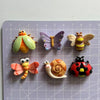 A collection of cute insect resin fridge magnets including a butterfly, bee, snail, ladybug, and dragonfly.