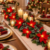 A festive display of red poinsettia garlands with warm white lights decorating a Christmas mantel or stair.