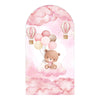 A watercolor illustration featuring a cute teddy bear floating among pink clouds and decorated with hot air balloons.