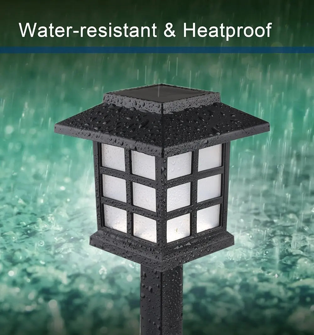 A black, square-shaped outdoor pathway light fixture with a grid of white lights is shown in the rain.