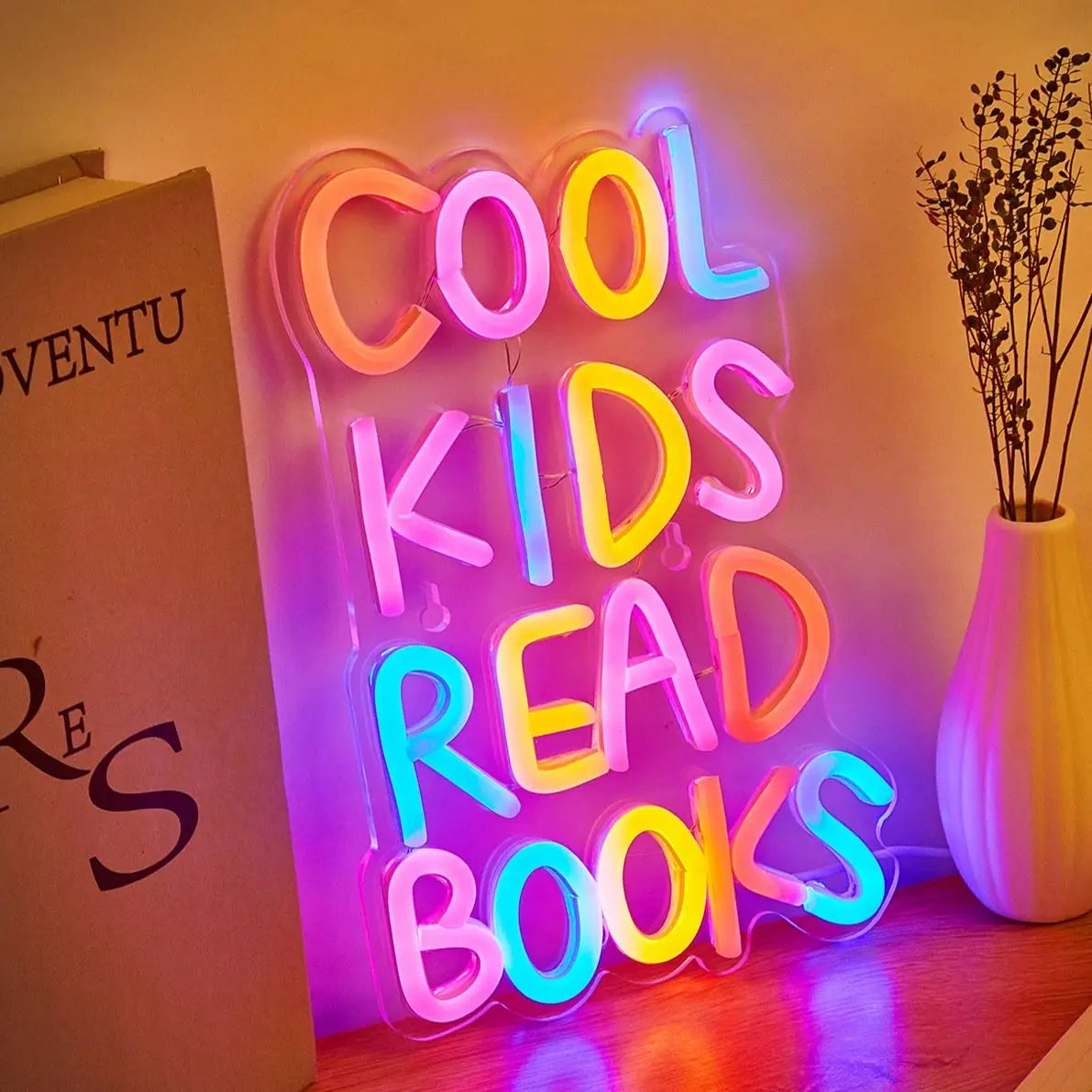 A neon sign spelling out COOL KIDS READ BOOKS illuminated on a wall.