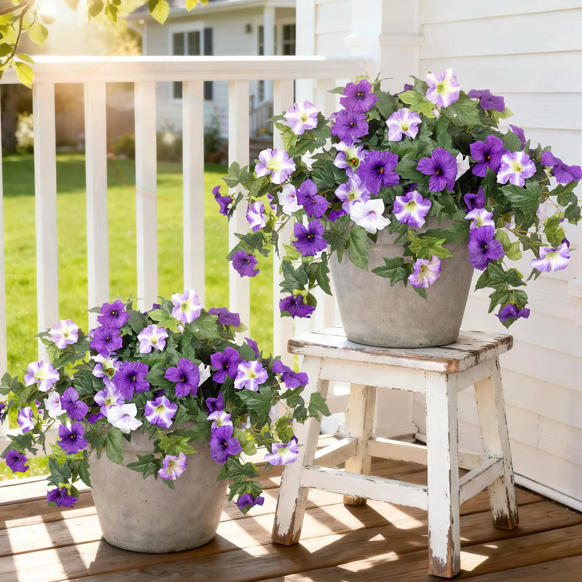 Purple and white artificial petunia bundles displayed in pots on a wooden deck.