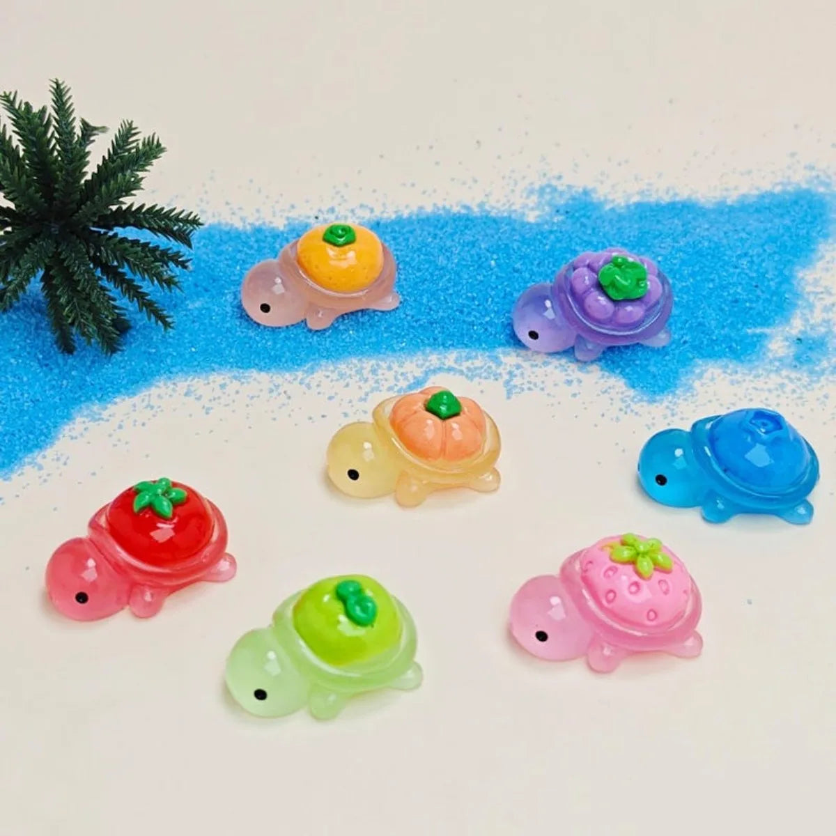 A collection of glow-in-the-dark fruit turtle resin charms in various colors like orange, purple, and pink scattered on a blu
