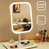 A white LED touch-sensitive vanity mirror with a round frame and a large capacity battery displayed on a bedside table.