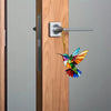 A colorful acrylic hummingbird suncatcher hanging ornament is displayed on a wooden door.