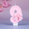 Glittery pink number eight birthday candle with a decorative pink bow on a white base