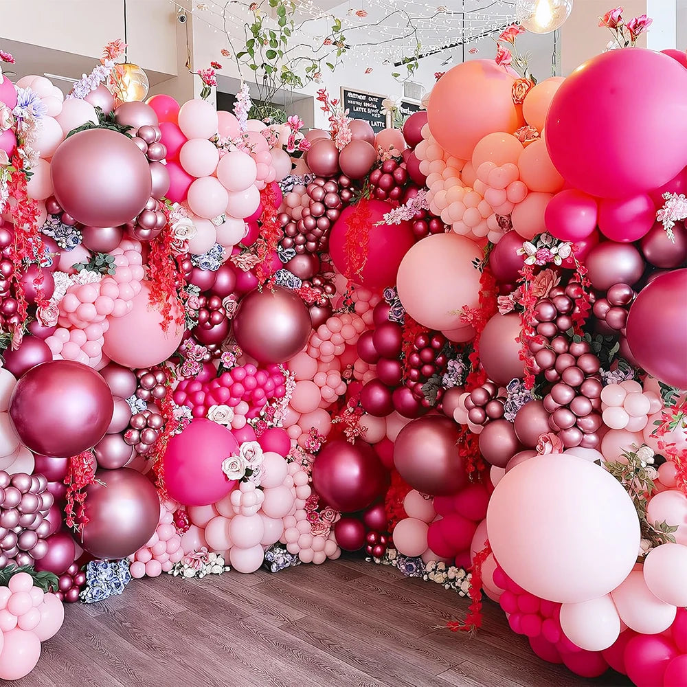 Un arrangement dense de ballons roses métalliques et or rose créant un fond floral pour un événement.