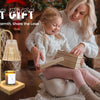 A woman is holding a child while using an elegant gold candle warmer lamp with a timer and adjustable height.