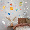 Pared de dormitorio decorada con estrellas y planetas luminiscentes y una planta en maceta.