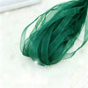 A bundle of dark green decorative fishtail yarn ribbon laid on a white surface.