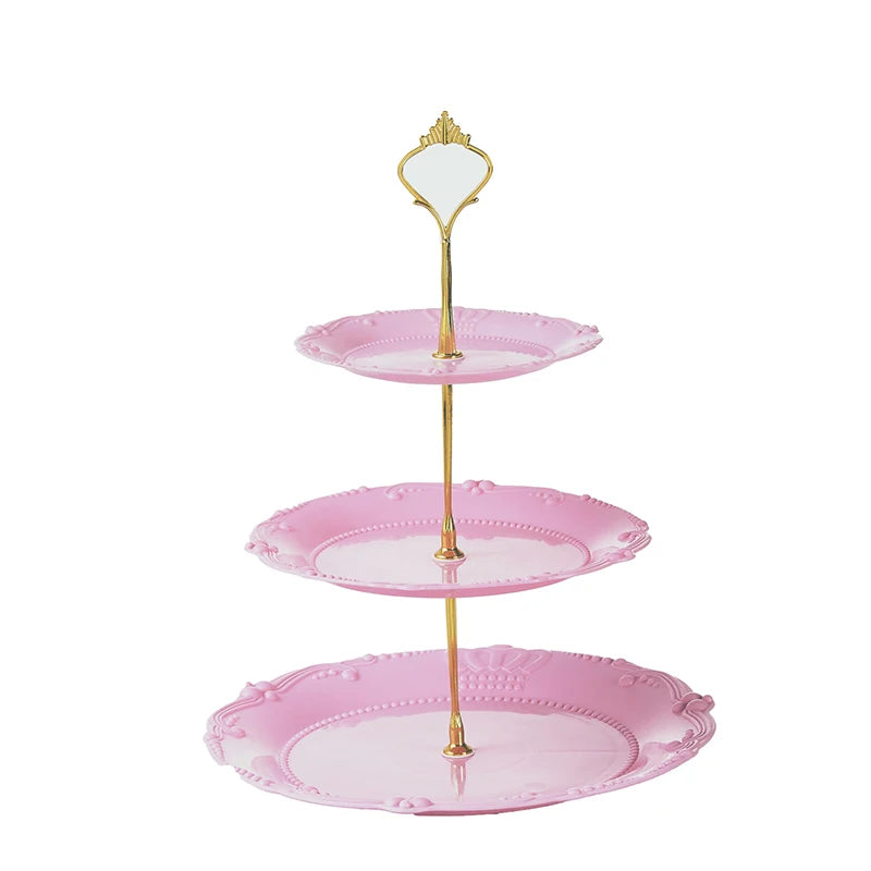 A three-tier pink plastic cupcake stand with a gold-colored mirror topper.