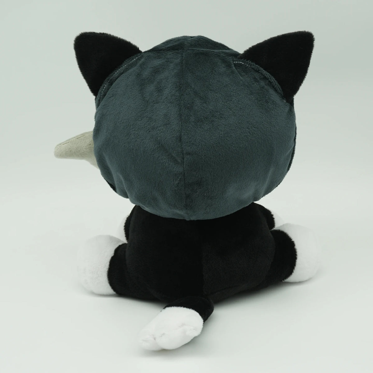 A dark gray plush toy resembling a cat's back with pointed ears and a white muzzle.
