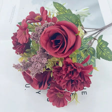 A bouquet of artificial deep red roses and purple chrysanthemum flowers.