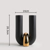 A black ceramic U-shaped tabletop vase with a gold accent, shown in a vertical view.