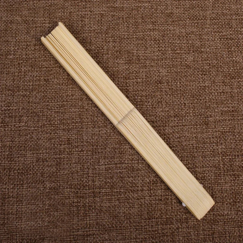 Un éventail main squelette en bambou pliante et mince posé sur un fond de tissu tissé marron.