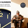A close-up of a large, dark blue modern silent quartz wall clock with gold accents on a light wall.