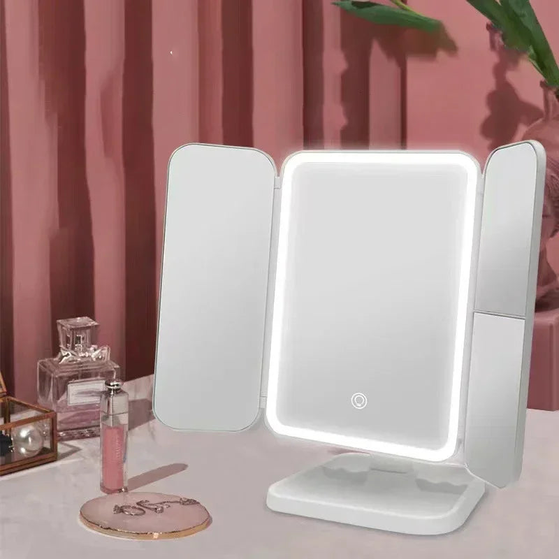 A white tri-fold LED makeup mirror with bright illumination is displayed on a table.