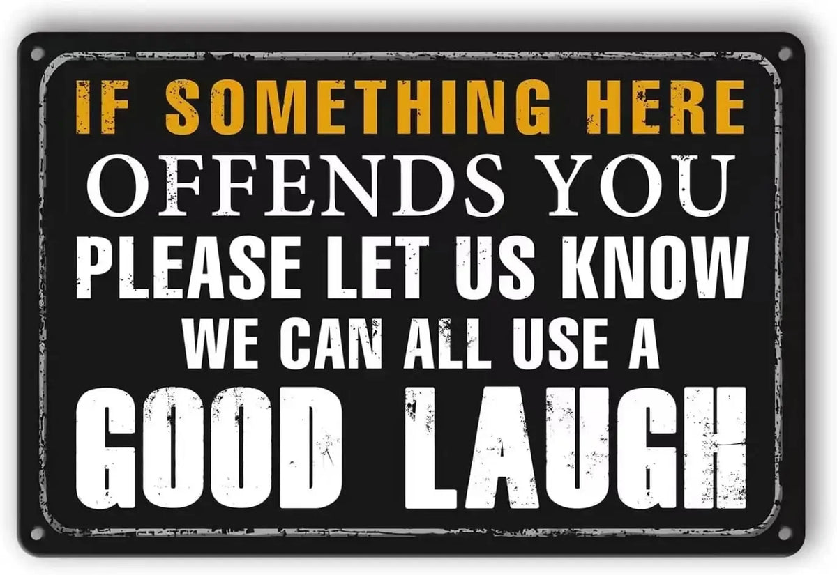 A black metal sign with yellow text that reads If something here offends you please let us know we can all use a good laugh
