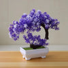 Artificial bonsai tree decoration with purple and white blossoms in a white planter