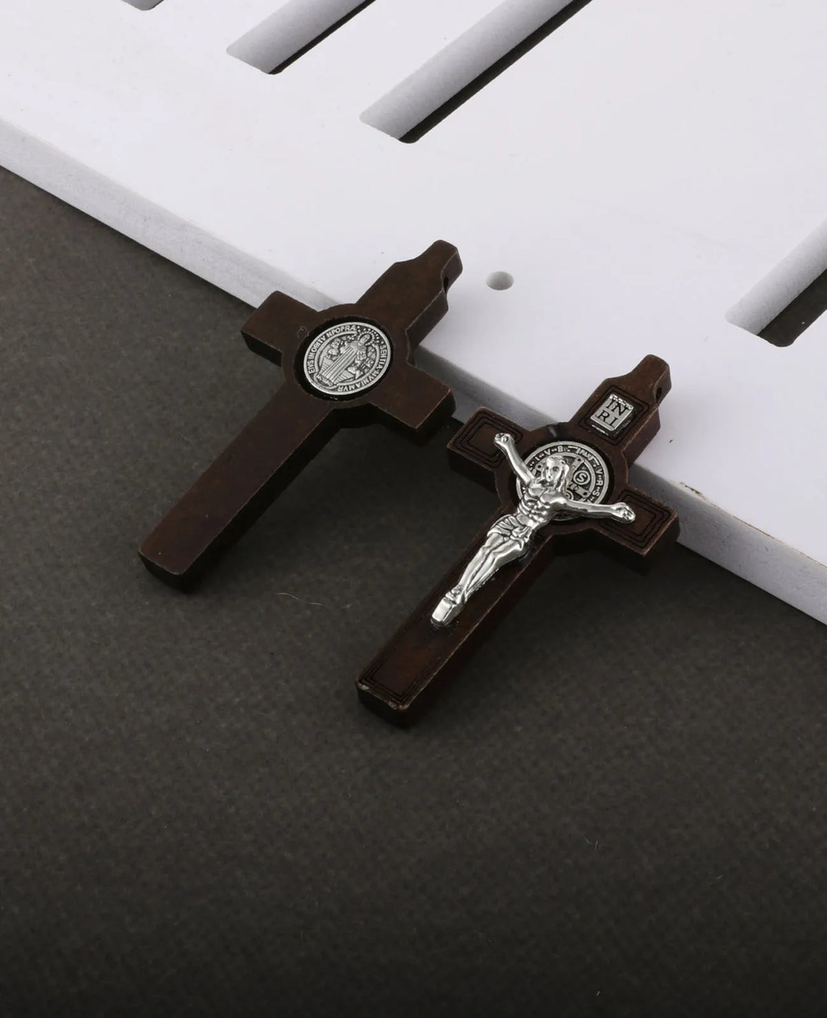 A set of wooden crucifix pendants featuring embossed religious imagery on a dark background.