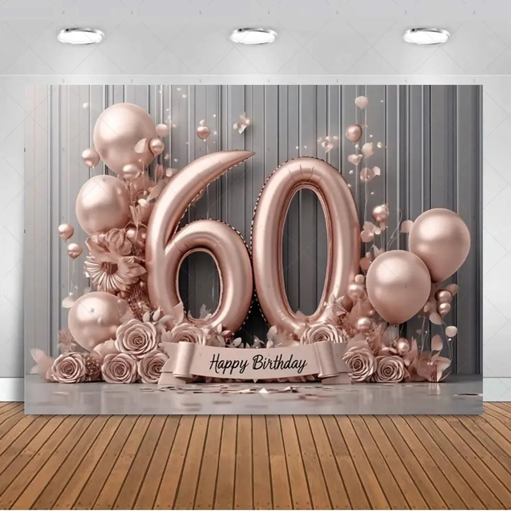 A backdrop for a 60th birthday featuring large gold balloons, pink roses, and sheer gold confetti against a gray wall.