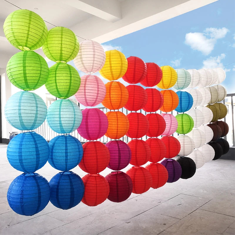 A display of decorative paper lanterns in various sizes and bright colors hanging along a wall.
