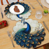 A set of four peacock feather placemats is displayed on a wooden table, featuring blue and green feathers for elegant dining 