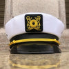 A white captain's hat with a black embroidered emblem and a black scarf displayed on a reflective surface.