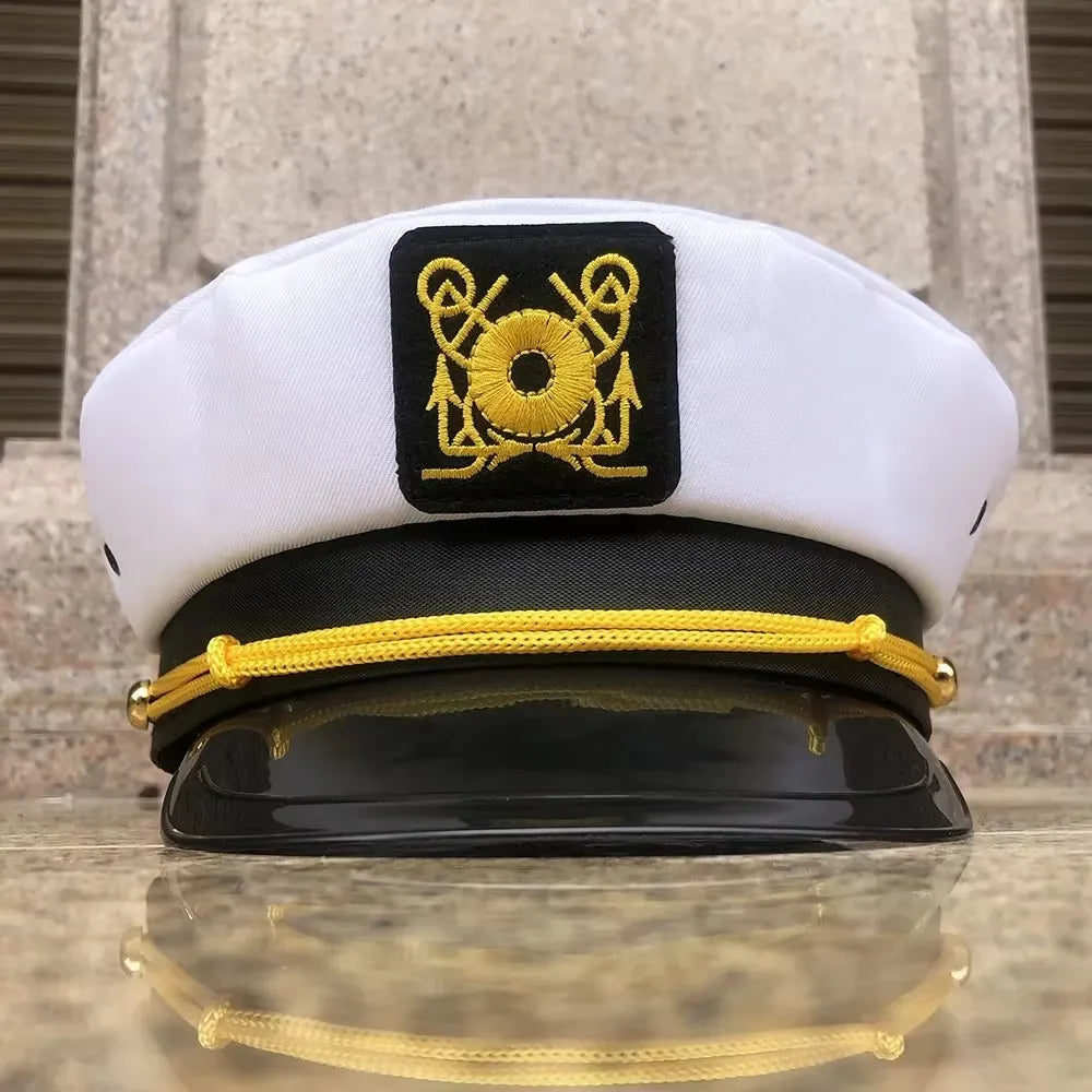 A white captain's hat with a black embroidered emblem and a black scarf displayed on a reflective surface.