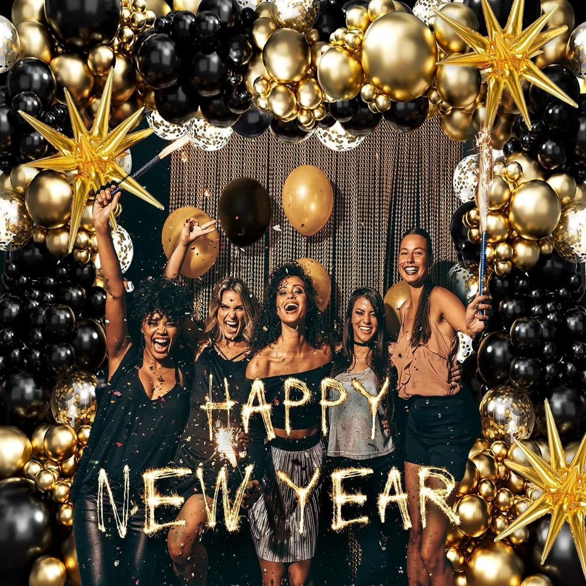 Five women pose in front of a black and gold balloon garland arch with starburst accents.