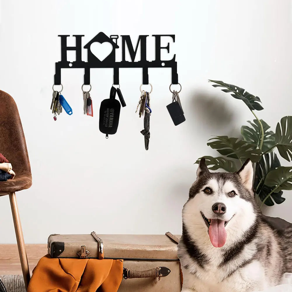 A white husky dog sits next to a black wall key holder with hooks on a wooden surface.