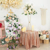 Gold geometric flower stands displaying white and pink floral arrangements on a draped table.