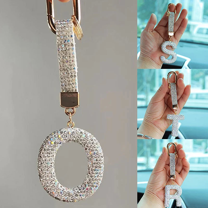 A sparkling crystal letter keychain charm in gold and silver tones, featuring a circular letter design.