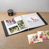 A DIY magnetic scrapbook album with several photos of family members and a baby lying on a blanket.