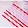 A collection of heart-shaped pink and red disposable straws arranged diagonally on a white surface.