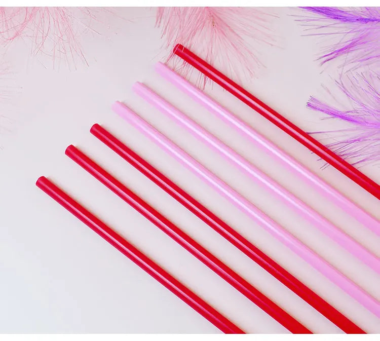 A collection of heart-shaped pink and red disposable straws arranged diagonally on a white surface.