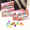 A set of essential oils in glass bottles and pink packaging with various colored oils displayed on a white surface.