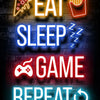 Neon alphabet signs spelling out EAT SLEEP GAME REPEAT on a brick wall background
