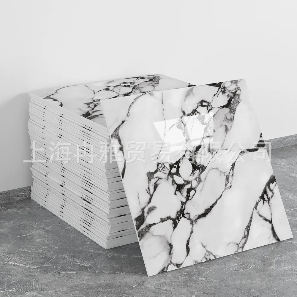 A stack of rectangular faux marble self-adhesive wall tiles with white and black veining on a gray surface.