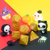 A set of seven polyhedral dice in various colors and shapes, including a witch hat die and a pumpkin die.