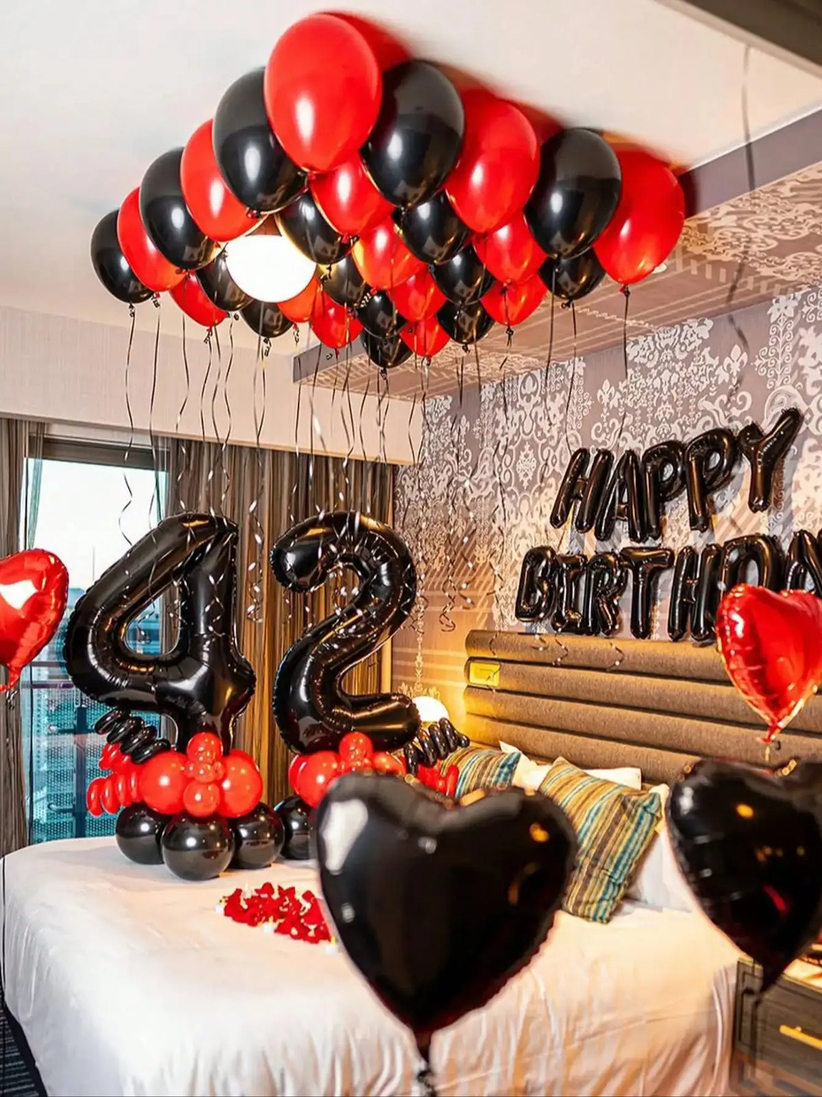 A balloon garland decoration featuring red and black foil number balloons above a birthday cake.