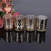 A set of four elegant glass votive candle holders with metallic silver and black patterned designs.
