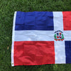 Großes Banner mit der Flagge der Dominikanischen Republik, blauen und roten Felder auf weißem Grund, auf grauem Untergrund