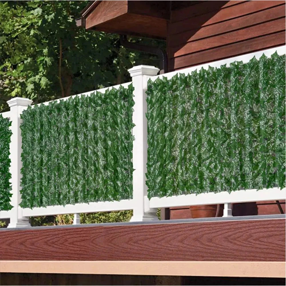 White fence panels featuring artificial green ivy hedge panels installed on a wooden deck.