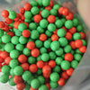 A close-up view of a pile of pastel foam beads in various shades of green and orange.
