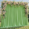 A lush floral backdrop featuring pink and white roses draped over a flowing lime green fabric curtain for an event.
