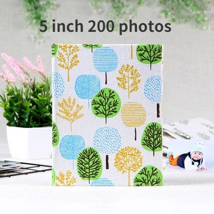 A square photo album cover featuring a pattern of colorful stylized trees in shades of green, blue, and yellow.